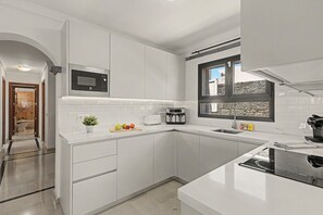 Eine moderne Küche mit weißen Schränken, einer eingebauten Mikrowelle, einem Toaster und einem Fenster mit Blick.