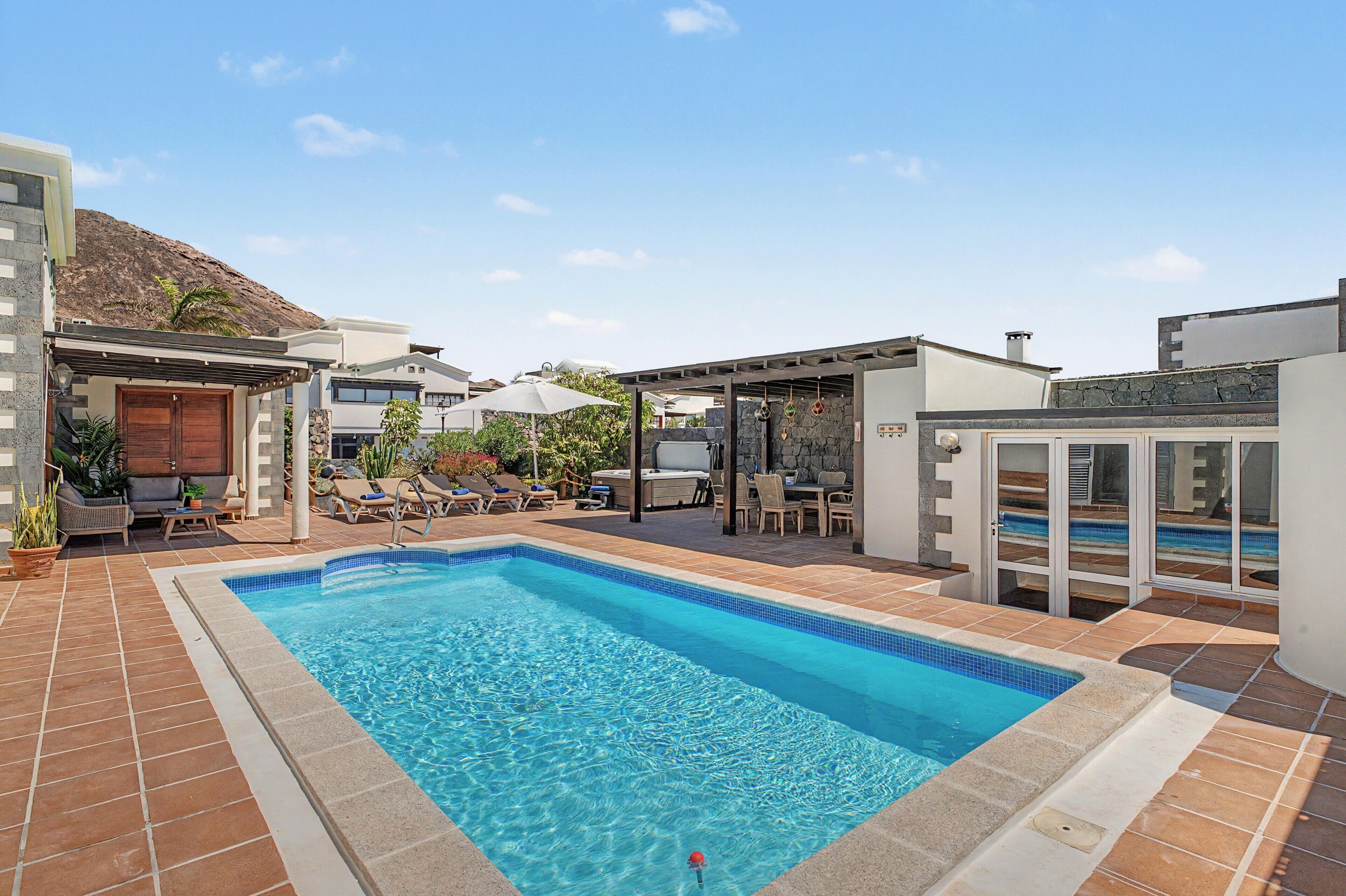 A swimming pool with lounge chairs and a hot tub area.