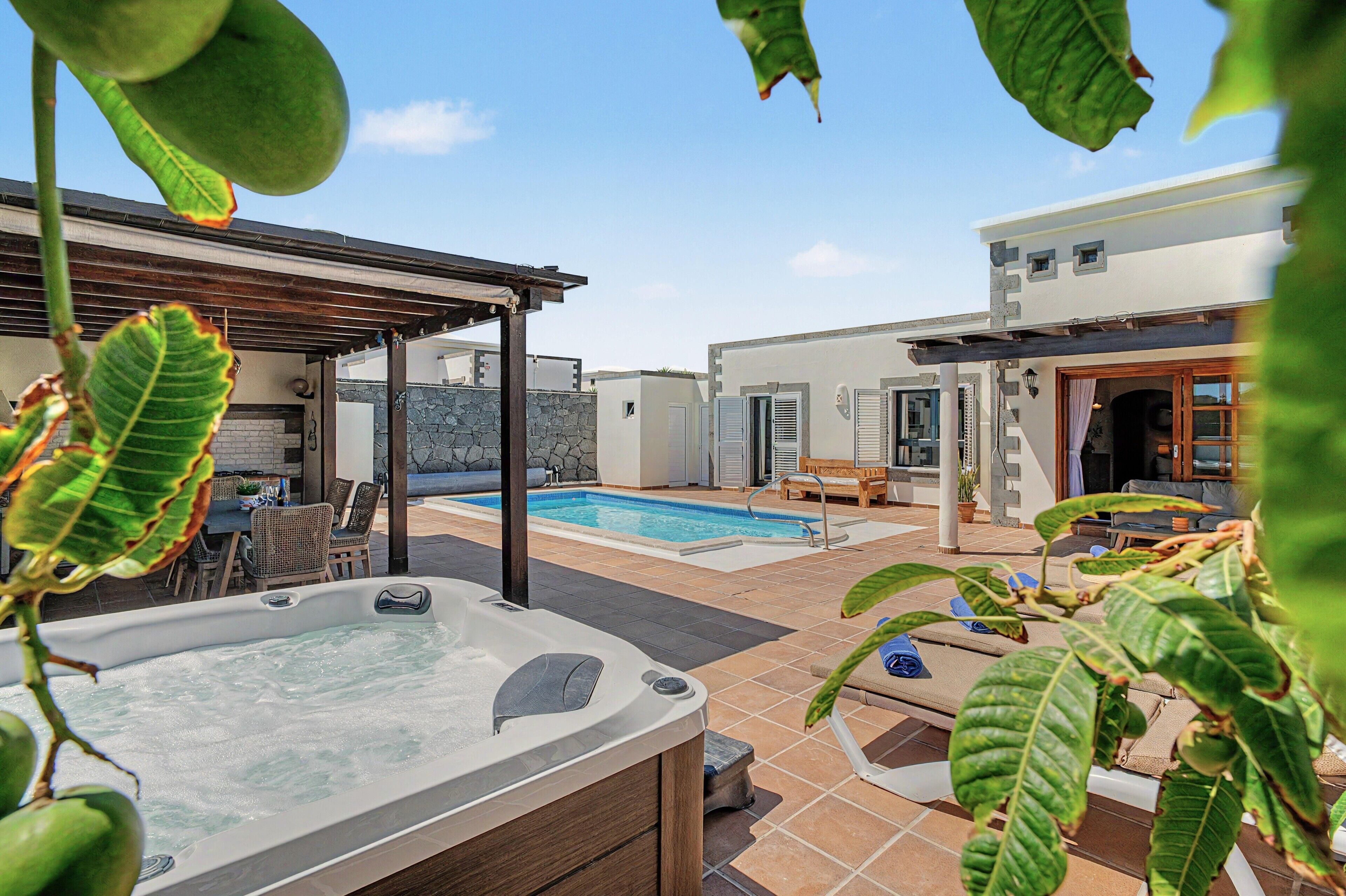 A backyard with a hot tub, a swimming pool, and outdoor seating.