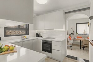 A modern kitchen with white cabinetry, a built-in dishwasher, and a window with a stone backsplash. - Vacation Villa 'Eire' with Mountain View, Wi-Fi and Air Conditioning (Yaiza)