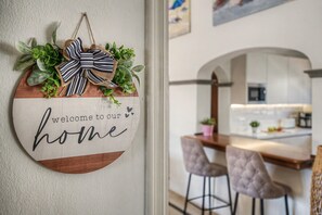 A circular welcome sign with a bow and greenery, a kitchen area with a microwave, and a dining space with chairs. - Vacation Villa 'Eire' with Mountain View, Wi-Fi and Air Conditioning (Yaiza)