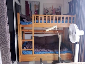 A bunk bed with a desk and chair, a standing fan, and a window with curtains. - Big Charming Suite with balcony in South Pattaya (Muang Pattaya)