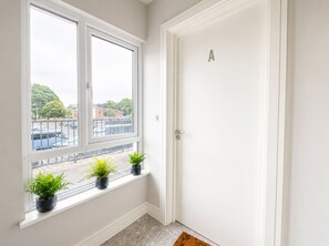 A room with a white door and a window with potted plants.