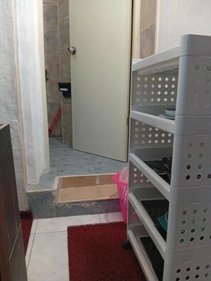A bathroom with a shower, a white door, a white shelf unit, and a red mat. - Charming Guest Room in South Pattaya - Pet-Friendly & Family-Oriented (Muang Pattaya)