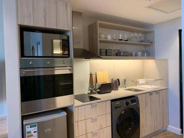 Una cocina moderna con electrodomésticos integrados, lavavajillas y un refrigerador compacto.