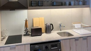 A modern kitchen with a built-in dishwasher, a coffee maker, and a sink. - Tranquil Foreshore Studio Fully Equipped & Central (Cape Town)