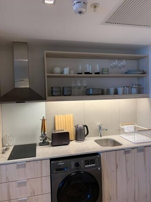Eine moderne Küche mit integriertem Geschirrspüler, einer Kaffeemaschine und einem Spülbecken.