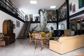 A spacious living area with a staircase, a sofa, a coffee table, and a piano.