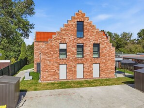 A modern brick building with a sloped roof, multiple windows, and a small balcony. - Ebbe&Flut - Modern Ebbe&Flut Vacation Rental in Norddeich for the Whole Family (Norden)
