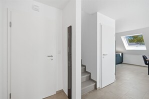A modern interior with white walls, a staircase, and a skylight. - Ebbe&Flut - Modern Ebbe&Flut Vacation Rental in Norddeich for the Whole Family (Norden)