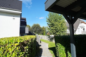 A residential area with a pathway leading to a house with a white exterior and a grey roof. - House at Badeweg 4 - "Sandkorn 1" Apartment (Scharbeutz)