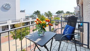 A balcony with a table, a chair, and a vase of flowers. - Seebrücke Apartment 11 - Seebrücke (Scharbeutz)