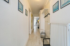 Ein Flur mit gerahmten Bildern an den Wänden, einem Heizkörper und einem kleinen Tisch mit Stuhl.