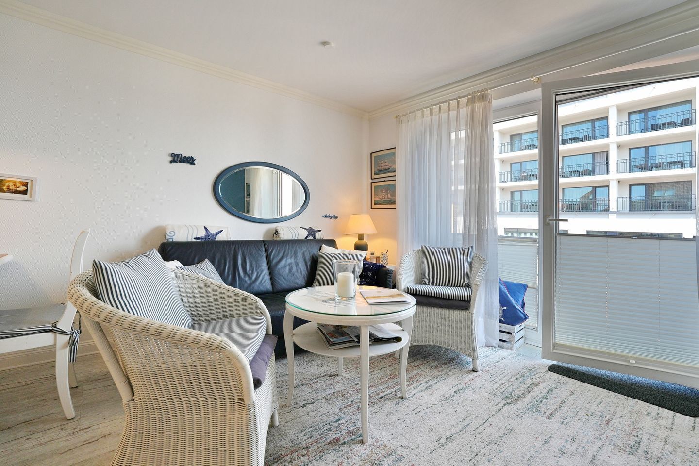 Moderni hotellihuone, jossa on sohva, pyöreä pöytä ja näkymä rakennuksen ulkopuolelle.