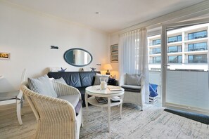 A modern hotel room with a sofa, a round table, and a view of the building's exterior. - Seebrücke Apartment 11 - Seebrücke (Scharbeutz)