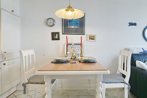 Ein Essbereich mit einem Holztisch, weißen Stühlen, einer Uhr und gerahmten Bildern an der Wand.