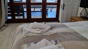 A room with a bed, a view of a pool and outdoor seating through a glass door, and a lamp on a bedside table. - Country Retreat with Pool & Braai, Sleeps 6 (Riebeek-Kasteel)
