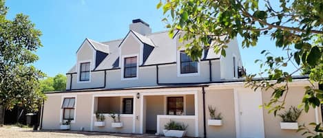 A two-story house with a symmetrical facade, multiple windows, and a gravel driveway.