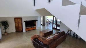 A spacious living area with a large sofa, a wooden cabinet, and a television. - Country Retreat with Pool & Braai, Sleeps 6 (Riebeek-Kasteel)