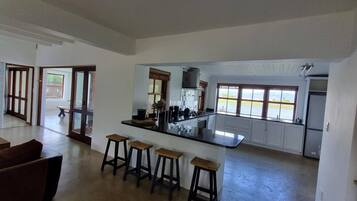 A spacious kitchen with a central island, bar stools, and large windows offering views.