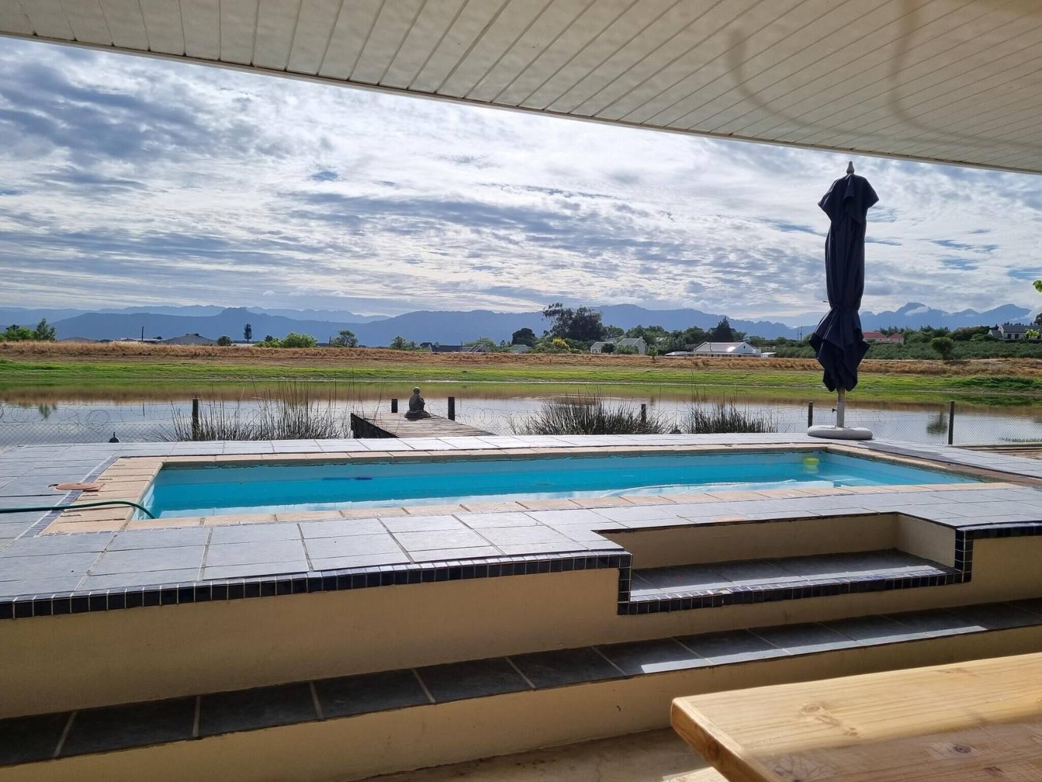 A swimming pool with a view of mountains and a cloudy sky.