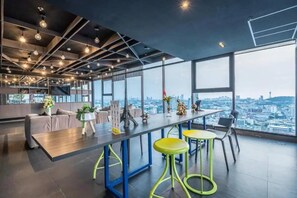 Ein modernes Interieur mit einem langen Tisch, Barhocker und großen Fenstern mit Blick auf die Stadt.