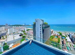 Ein Hochhaus mit Pool auf dem Dach, mit Blick auf die Stadt und das Meer.