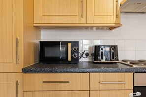 A kitchen with wooden cabinets, a microwave, and a toaster. - West Bridgford Luxury 2 bed 2 Bath Apartment (Nottingham)