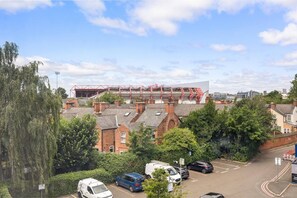 A residential area with houses, parked cars, and a large sports stadium in the background. - West Bridgford Luxury 2 bed 2 Bath Apartment (Nottingham)