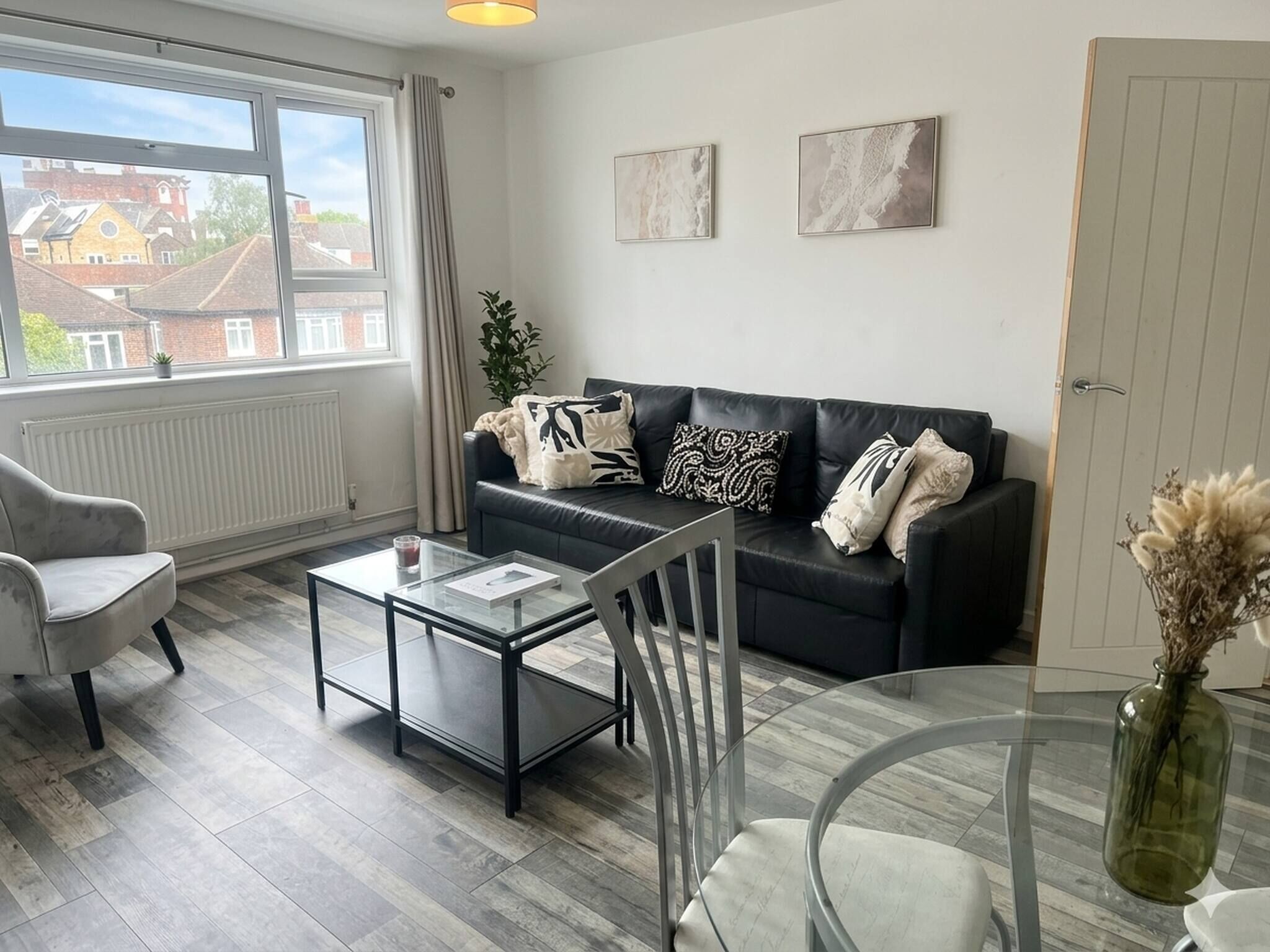 A modern living room with a sofa, armchairs, a glass coffee table, and a view of the outside.