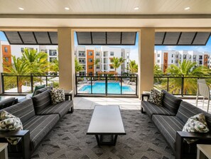 Ein Balkon mit Blick auf einen Pool, ausgestattet mit Sofas und einem Couchtisch.