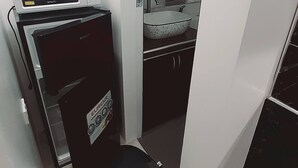 Ett litet, praktiskt pentry med mikrovågsugn, ett litet kylskåp och en diskho.
