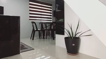 A modern interior with a staircase, a dining area with chairs and a table, and a potted plant.