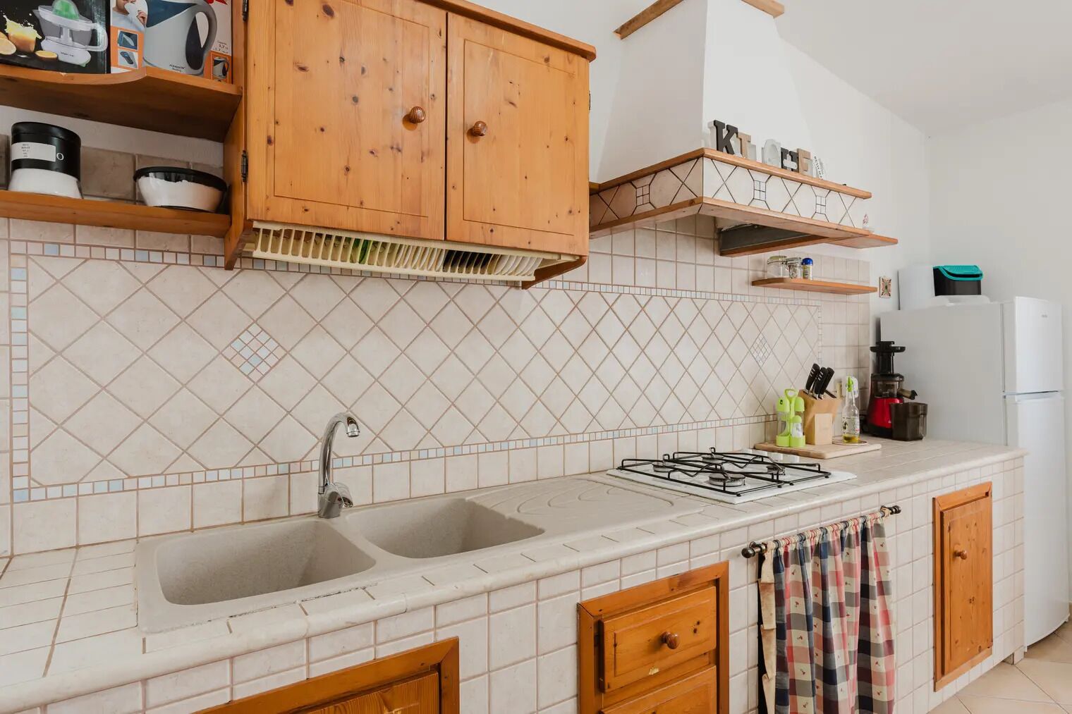 Eine Küche mit zwei Spülen, Holzschränken, einem Gasherd und einem Kühlschrank.