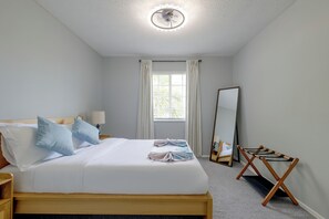 A hotel room with a bed, a bedside table, a lamp, a mirror, and a window with curtains. - Kissimmee Family Fun w/ Private Pool & Pond Views! (Kissimmee)