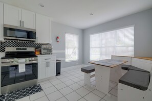 A modern kitchen with white cabinetry, a built-in oven, a microwave, and a stove. There is a small trash bin and a window with blinds. - Kissimmee Family Fun w/ Private Pool & Pond Views! (Kissimmee)