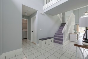 A modern interior with a staircase, a bench, and a kitchen area. - Kissimmee Family Fun w/ Private Pool & Pond Views! (Kissimmee)