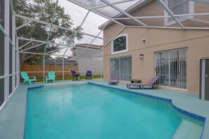 An indoor swimming pool with a covered area, surrounded by lounge chairs and a wooden fence. - Kissimmee Family Fun w/ Private Pool & Pond Views! (Kissimmee)