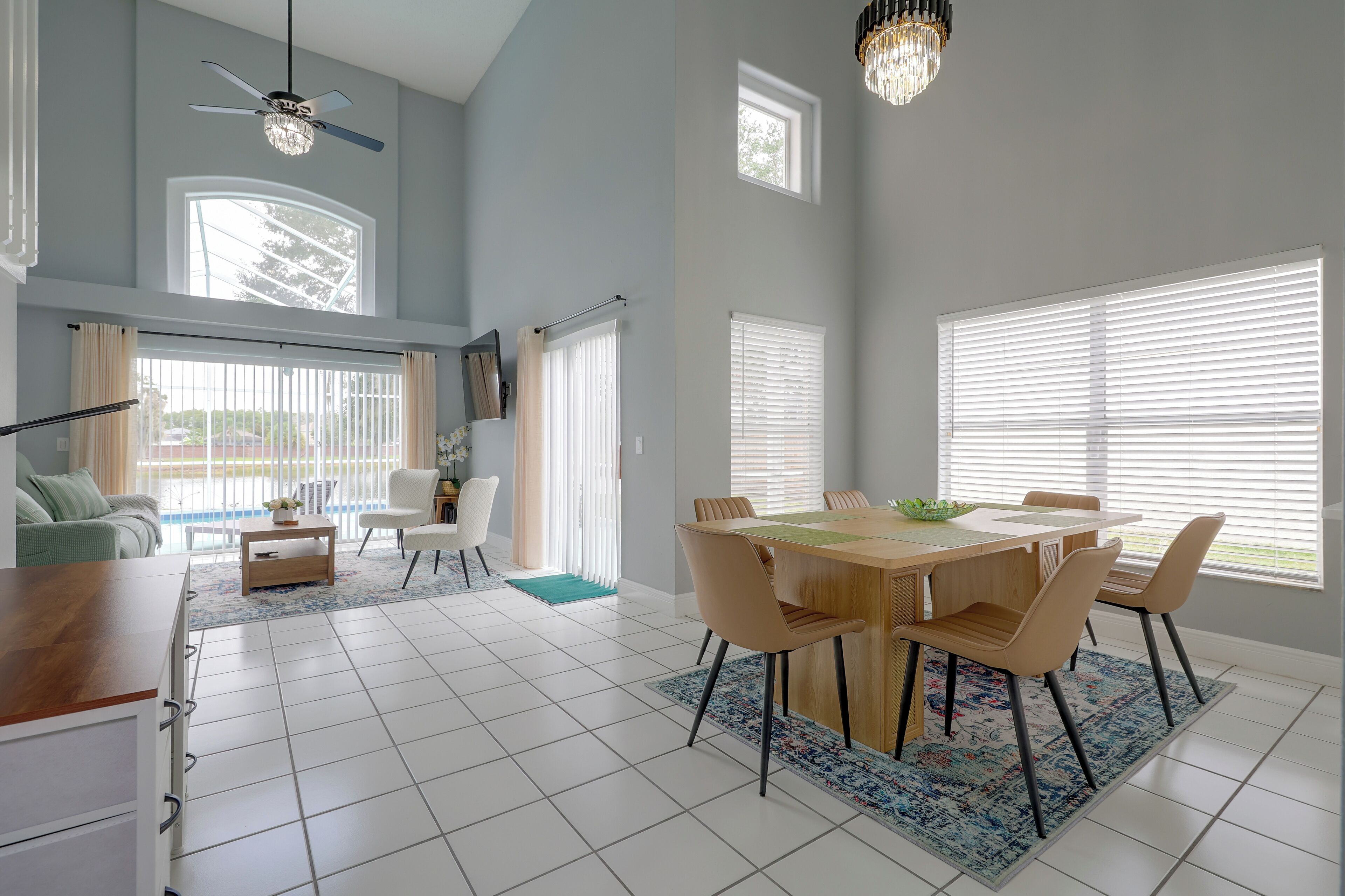 A spacious living area with a dining table, chairs, and a ceiling fan.