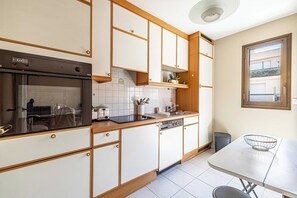 A modern kitchen with white cabinets, a built-in oven, a sink, and a window overlooking a balcony. - Cozy Apartment Near Sea 4P - Cannes (Cannes)