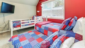 Ein Schlafzimmer mit roter Wand, einem weißen Bett und einem an der Wand montierten Fernseher.
