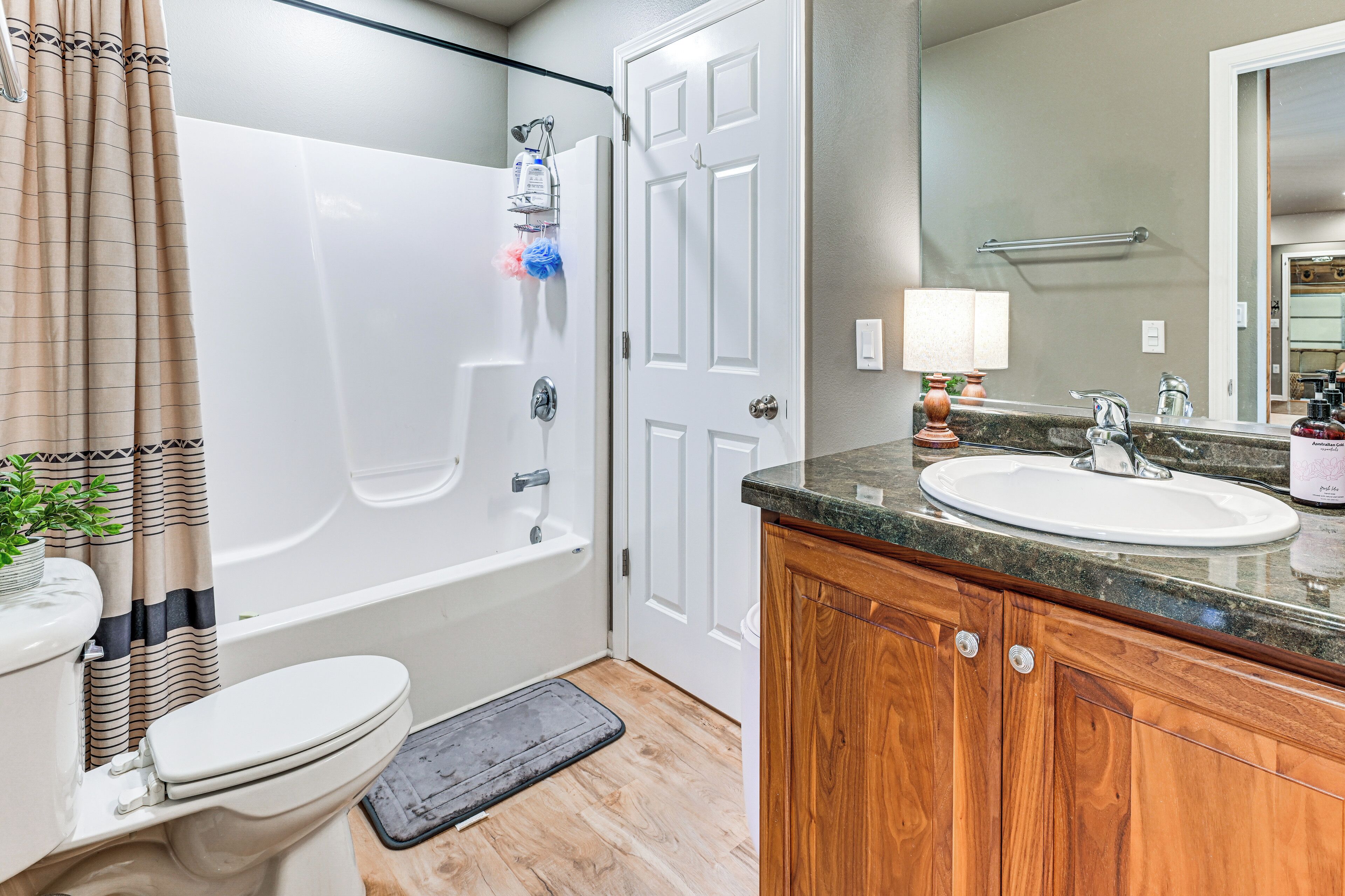 Baño con bañera, inodoro y tocador con lavabo y espejo.