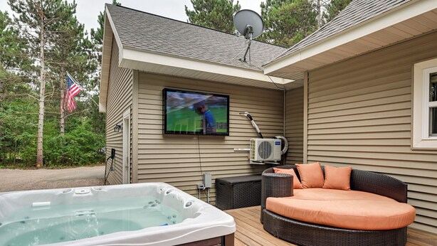 Eine Terrasse mit Whirlpool, Sitzgelegenheit im Freien und einem an der Wand befestigten Fernseher.