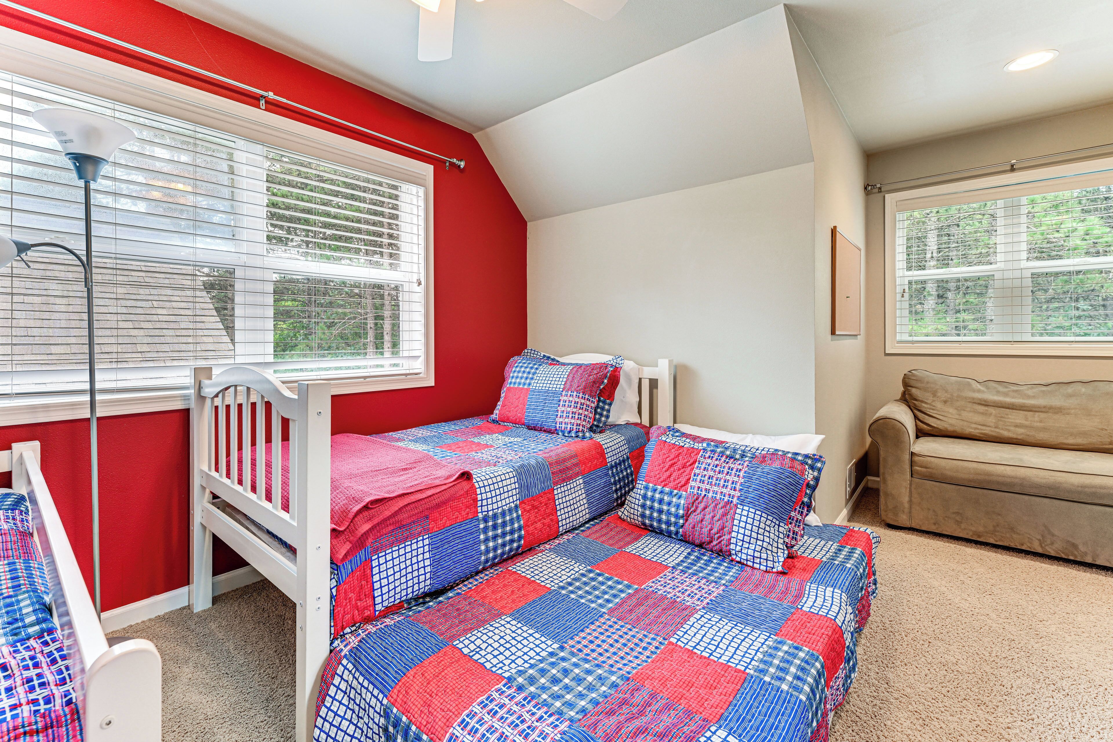 A child's bedroom with a bunk bed, a window with blinds, a ceiling fan, and a sofa.