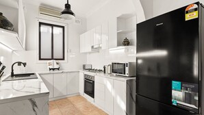 Eine moderne Küche mit weißen Schränken, einem schwarzen Kühlschrank und einer Mikrowelle.
