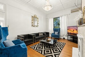 Ein modernes Wohnzimmer mit einem schwarzen Leder-Modulsofa, einem blauen Sessel, einem Glastisch und einem schwarz-weißen Teppich.