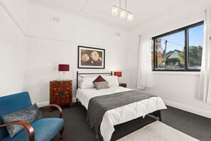 A bedroom with a bed, bedside tables, a chair, a dresser, a window, and a painting on the wall. - Spacious 4-Bed Character House in Vibrant Stanmore (Stanmore)