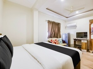 Ein Hotelzimmer mit einem Bett, einem Schreibtisch, einem Fernseher und einem Deckenventilator.