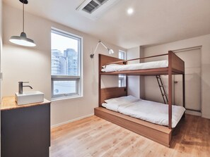 Habitación con literas, una ventana, un escritorio con lavamanos y una lámpara colgante.
