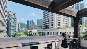 A rooftop terrace with a bar area, seating, and a view of the cityscape. - Susu House (Seoul)